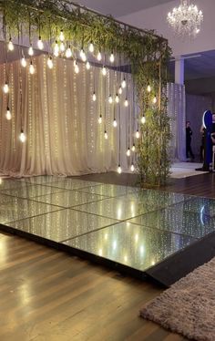 a dance floor with lights hanging from it's ceiling and people standing in the background