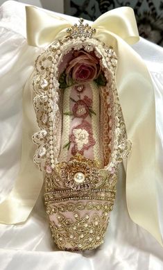 a close up of a shoe on a bed with a white satin ribbon around it