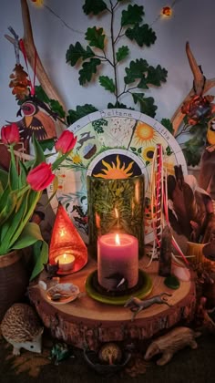 a lit candle sitting on top of a wooden table surrounded by plants and other decorations