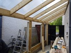 a man is working on the side of a building with wood framing and glass roof