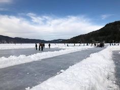people are skating on an icy lake with mountains in the background and blue skies above