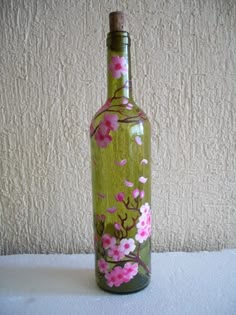 a green bottle with pink flowers painted on it