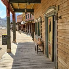 an old western town with wooden buildings and rocking chairs on the front porch, looking out onto the street