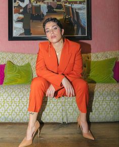 a woman in an orange suit sitting on a couch