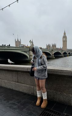 a woman standing on the edge of a bridge looking at her cell phone in london