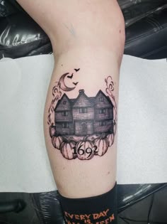 a tattoo on the leg of a person with a house and pumpkins around it