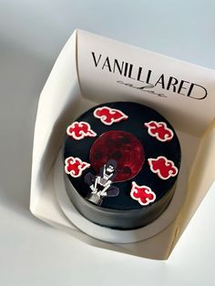 a small round cake in a box with red and black designs on it's surface