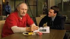 an older man sitting at a table next to a young boy in a red shirt