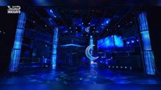 an empty stage is lit up with blue lights and the moon in the center, surrounded by columns