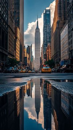 a city street with tall buildings reflecting in the water