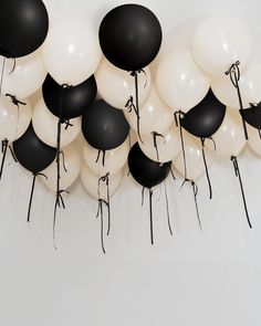 black and white balloons are arranged in the shape of a wall hanging from a ceiling