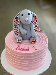 a pink cake with an elephant on top and sprinkles around the edges