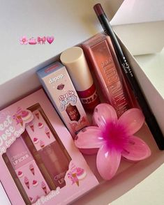 the contents of a beauty box are displayed on a white surface with pink flowers and lipstick