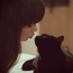 a woman holding a black cat in her lap with the caption nose kisses mommy