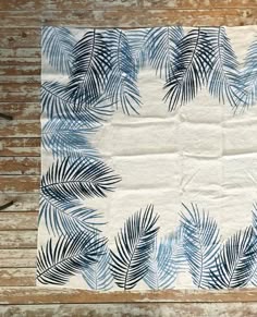 a piece of paper with blue palm leaves on it sitting on a wooden table next to scissors