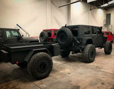 two jeeps are parked in a garage with large tires on the front and sides