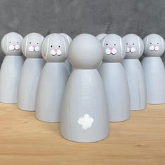 a group of small white rabbits sitting on top of a wooden table next to each other