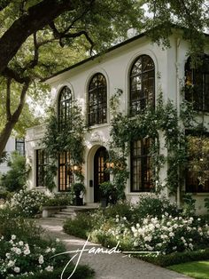 a white house surrounded by trees and flowers