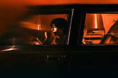 a man sitting in the passenger seat of a car looking out the window at something