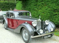 an old car is parked in front of some bushes