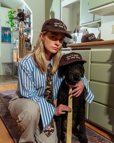 a woman sitting on the floor with her dog wearing a hat and tie that says,
