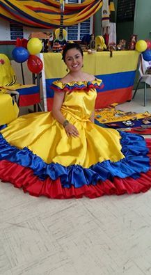 a woman in a yellow and blue dress sitting on the floor with balloons around her