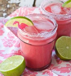 two margaritas with lime slices on the rim and one has a pink drink in it