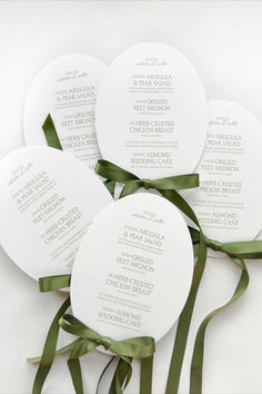 four white paper fans with green ribbons tied around them on top of each other in front of a white background