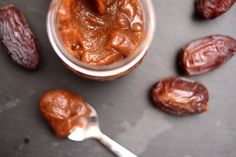 a jar filled with peanut butter next to some raisins and a spoon on a table