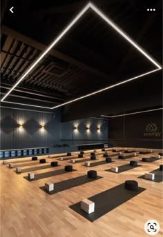 an empty room with rows of yoga mats on the floor and lights hanging from the ceiling