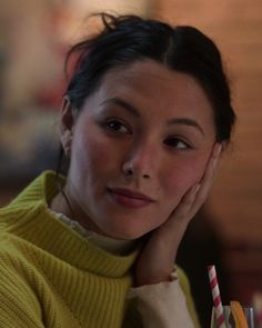 a woman holding a straw and looking at the camera with her hand on her face