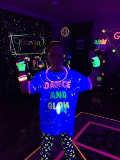 a young boy standing in a room with neon lights on his shirt and leggings