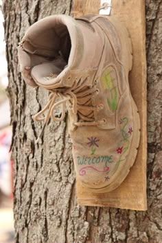 a pair of shoes that are hanging on a tree trunk with graffiti written on them