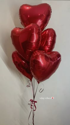 a bunch of red heart shaped balloons tied to a wall
