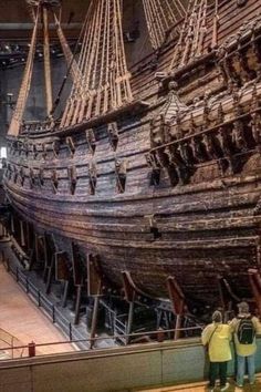 two people looking at an old ship in a museum