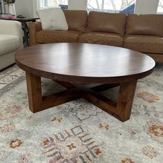 a wooden table sitting on top of a rug in a living room next to a couch