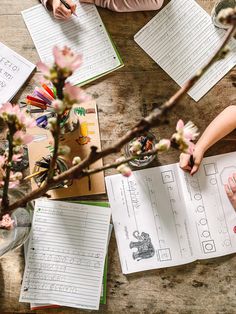 two children are doing their homework at the table with flowers and paper work on it