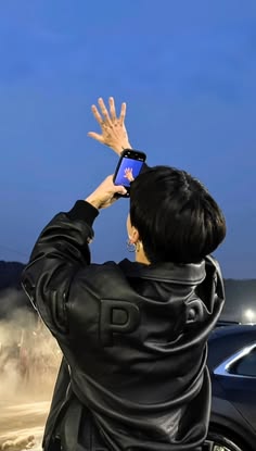 a woman taking a photo with her cell phone while standing in front of a car
