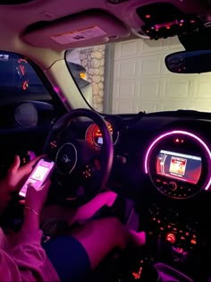 a person sitting in a car holding a cell phone and looking at the screen while driving
