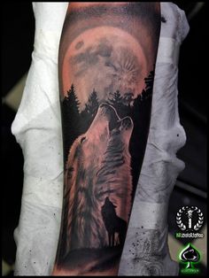a man's arm with a wolf tattoo on it and the moon in the background