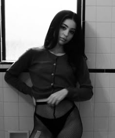 a woman in fishnet stockings and tights standing next to a bathroom window with her hands on her hips