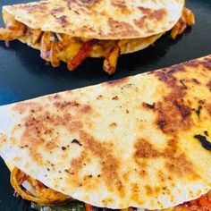 two quesadillas sitting on top of a black plate
