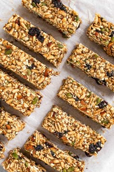 homemade granola bars are lined up on a sheet of parchment paper, ready to be eaten