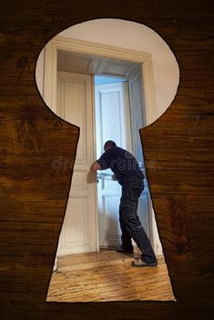 a man standing in front of a keyhole on a wooden wall royalty images and stock photography