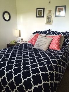 a bed with blue and white comforter in a bedroom next to pictures on the wall