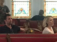 people sitting in pews at a church with stained glass windows and stain glass behind them