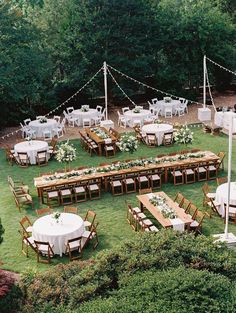 an outdoor wedding reception setup with tables and chairs set up in the grass, surrounded by greenery