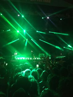 a large group of people at a concert with bright lights on the stage and in front of them
