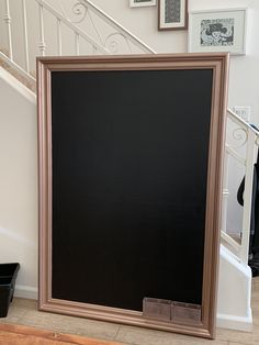 a large framed chalkboard sitting in front of a staircase