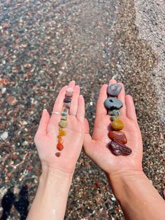 two hands holding rocks in the middle of a body of water with pebbles on them